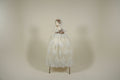 Elegant beige evening gown with floral details on a mannequin against a white draped background