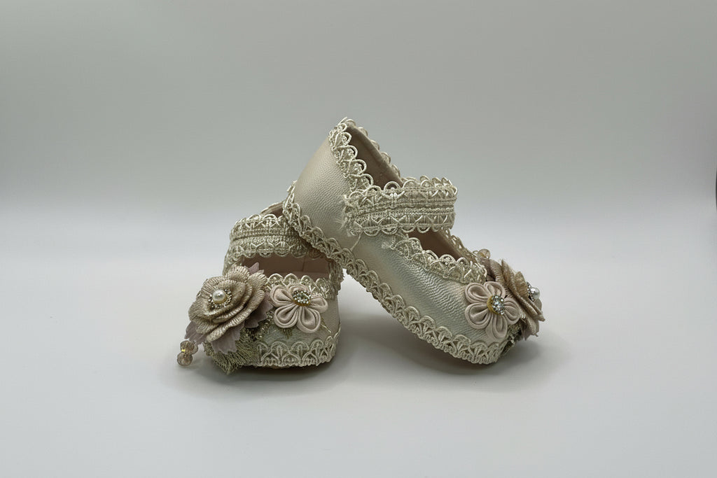Pair of beige lace-up shoes with floral details on a light gray background