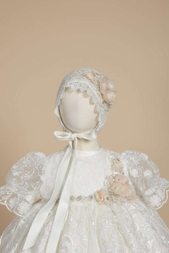 Mannequin wearing a white lace dress with floral details in a room setting.